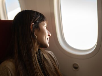 Frau sitzt im Flugzeug und schaut aus dem Fenster | © GettyImages/FG Trade