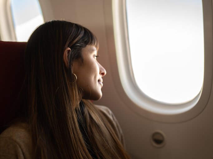 Frau sitzt im Flugzeug und schaut aus dem Fenster | © GettyImages/FG Trade