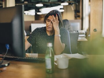 Müde Geschäftsfrau sitzt am Schreibtisch | © Getty Images/	Maskot