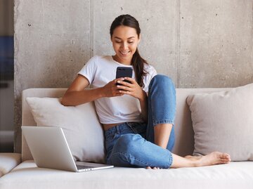 Frau sitzt auf der Couch und surft am Handy | © Dean Drobot/Shutterstock