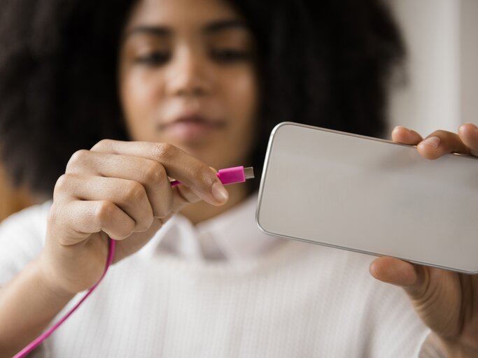 Frau lädt ihr Handy auf | © Getty Images/JGI/Jamie Grill