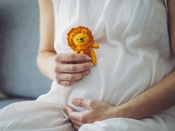 Schwangere Frau hält sich Löwe-Kuscheltier vor den Bauch | © Getty Images/Eva-Katalin