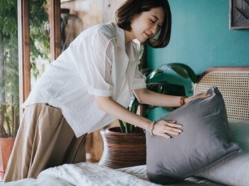 Junge Frau macht das Bett | © Getty Images/AsiaVision