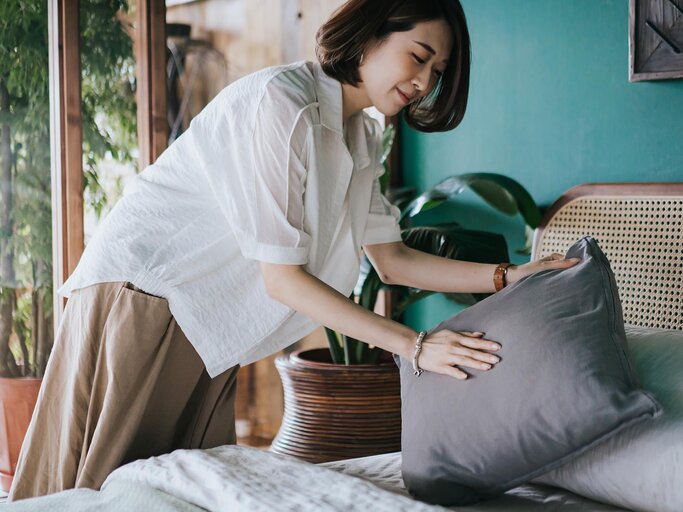 Junge Frau macht das Bett | © Getty Images/AsiaVision