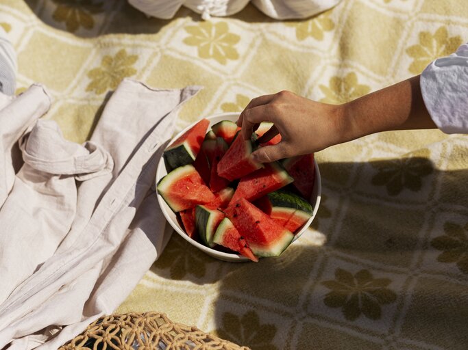 Frau greift in Schüssel mit Wassermelone | © GettyImages/Johner Images