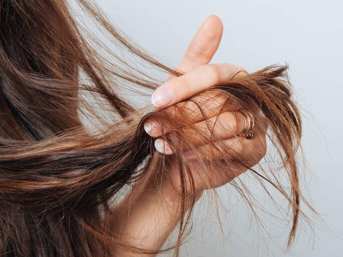 Frau hält sich die Haarspitzen | © gettyimages.de / Cristalov