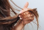 Frau hält sich die Haarspitzen | © gettyimages.de / Cristalov