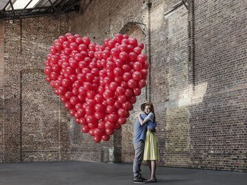 Paar in einem Lager mit roten Luftballons | © GettyImages/Anthony Harvie