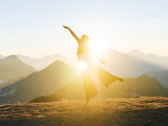 Frau tanzt im Sonnenaufgang | © GettyImages/	Ascent/PKS Media Inc.