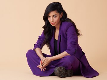 Collien Ulmen-Fernandes sitzt für ein Fotoshooting auf dem Boden in einem lila Anzug und schaut in die Kamera. | © ENTSCHIEDEN. Gegen Krebs