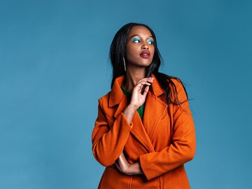 Modebewusst Frau mit orangenen Mantel | © GettyImages/Phamai Techaphan