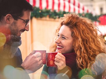 Verliebtes Paar trinkt Glühwein auf dem Weihnachtsmarkt | © GettyImages/	Marco_Piunti