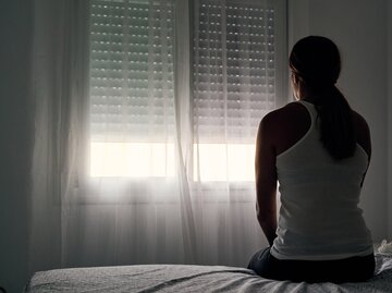 Frau sitzt in Dunkelheit im Schlafzimmer | © GettyImages/	Alvaro Medina Jurado