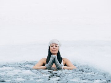 Frau beim Eisbaden mit Mütze und Handschuhen | © AdobeStock/Girts