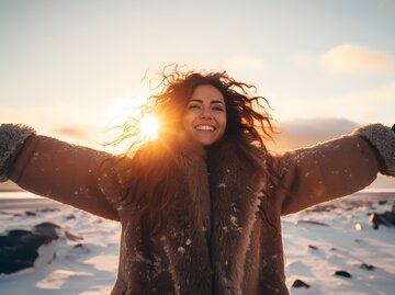 Frau mit offenen Armen in der Wintersonne | © AdobeStock/Jens/KI generiert