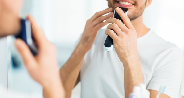 Mann rasiert sich vorm Spiegel mit Elektrorasierer | © shutterstock/Syda Productions