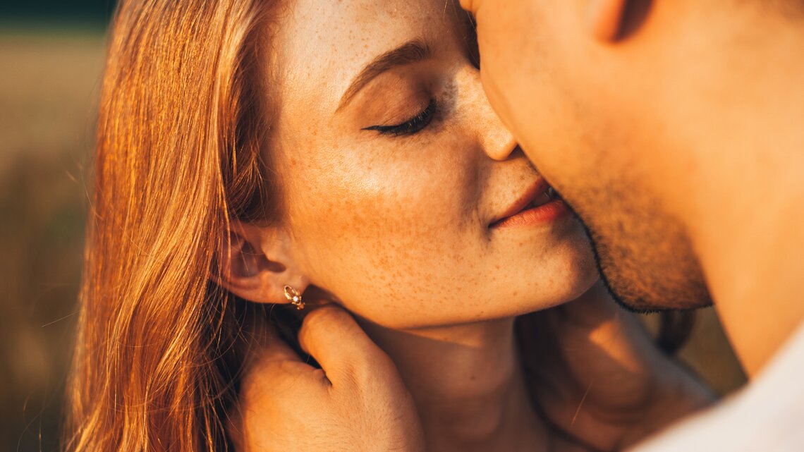 Sommersprossige Frau küsst ihren Freund in der Natur | © 	GettyImages/Strelciuc Dumitru