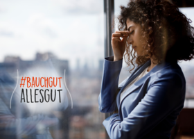 Gestresste Frau steht am Fenster.