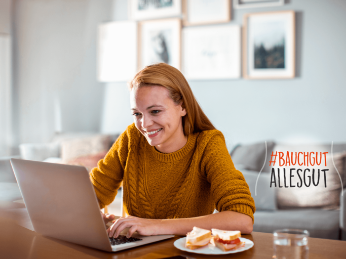 Junge Frau isst ihr Frühstück vor dem Laptop. | © iStock.com / Geber86