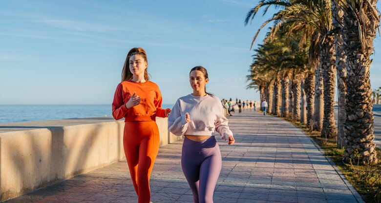 Zwei Frauen in sportlicher Kleidung gehen in Spanien zusammen joggen | © GettyImages/	urbazon