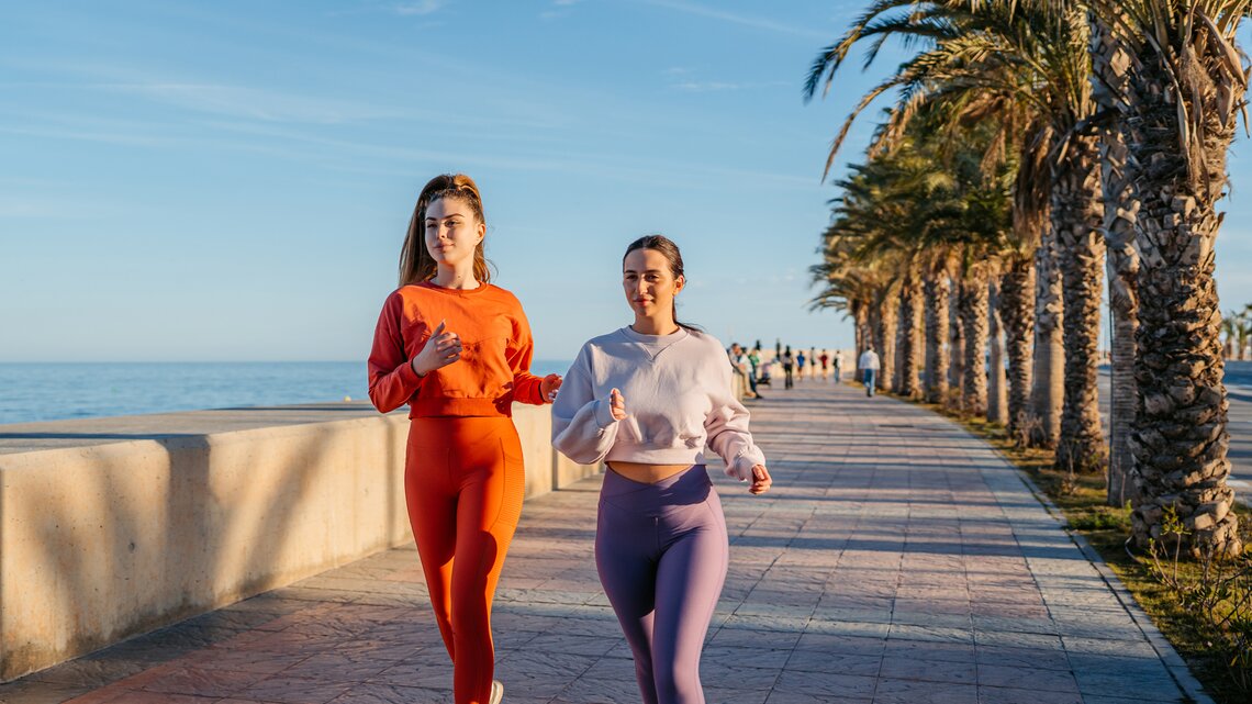 Zwei Frauen in sportlicher Kleidung gehen in Spanien zusammen joggen | © GettyImages/	urbazon