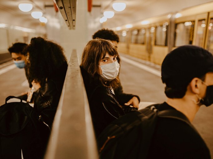 Menschen sitzen mit Corona-Maske auf Bank in der U-Bahn-Station | © Getty Images/Maskot