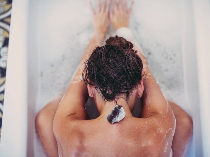 Frau mit nassen Haare trägt Dutt in der Badewanne | © Getty Images/Guido Mieth