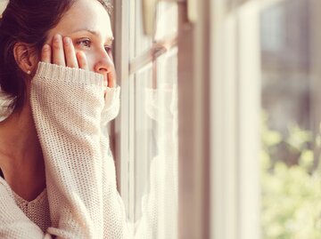 Frau blickt traurig aus dem Fenster | © Getty Images/martin-dm
