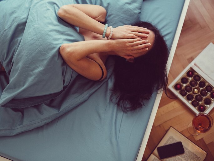 Frau liegt traurig im Bett | © Getty Images/martin-dm