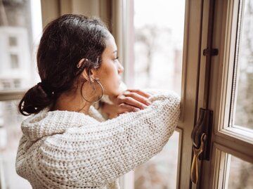 Frau blickt gedankenverloren aus dem Fenster | © Getty Images/franckreporter