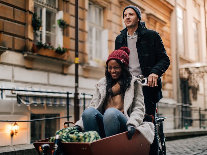 Paar mit Cargo-Bike unterwegs und hat Spaß | © Getty Images/AleksandarNakic