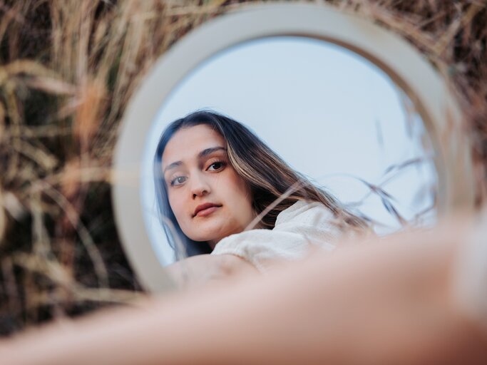 Frau blickt nachdenklich in den Spiegel | © Getty Images/Patricio Nahuelhual
