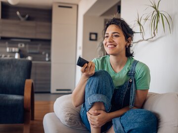 Frau sitzt auf der Couch und schaut Serien  | © Getty Images/MixMedia