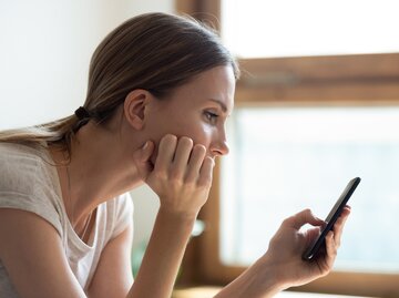 Frau guckt besorgt auf ihr Handy | © Getty Images/fizkes