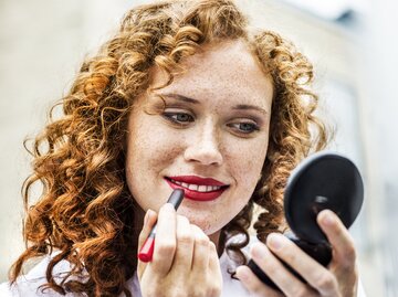 Frau trägt sich Lippenstift auf | © Getty Images/Westend61