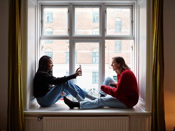 Junge Frau zeigt Freundin etwas auf dem Smartphone | © Getty Images/Klaus Vedfelt