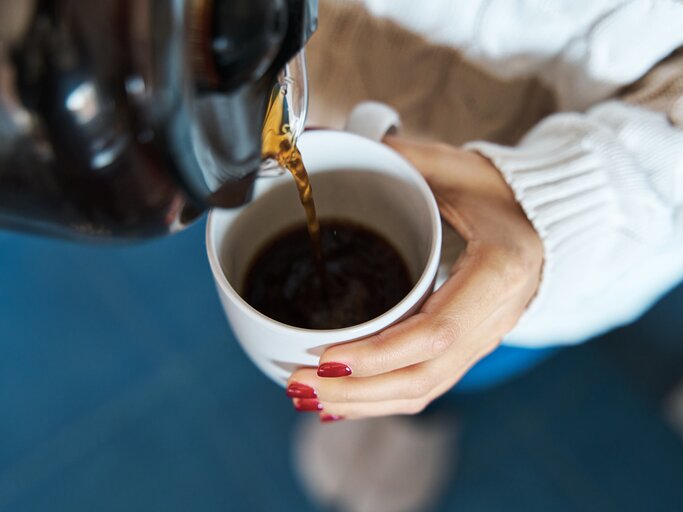 Frau schenkt sich Filterkaffee in Tasse ein | © Getty Images/juanma hache
