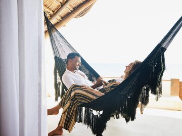 Mann und Frau lachen zusammen in der Hängematte | © Getty Images/Thomas Barwick