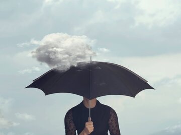 Frau hat schwarzen Regenschirm vor das Gesicht gezogen | © Getty Images/fcscafeine