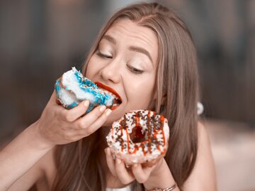 Junge Frau isst zwei Donuts | © Getty Images/	stock_colors