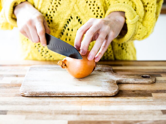 Frau schneidet auf einem Brett eine Zwiebel | © Getty Images/	Photographer, Basak Gurbuz Derman