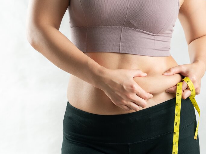 Frau mit Maßband und Fettpölsterchen am Bauch | © Getty Images/	PORNCHAI SODA