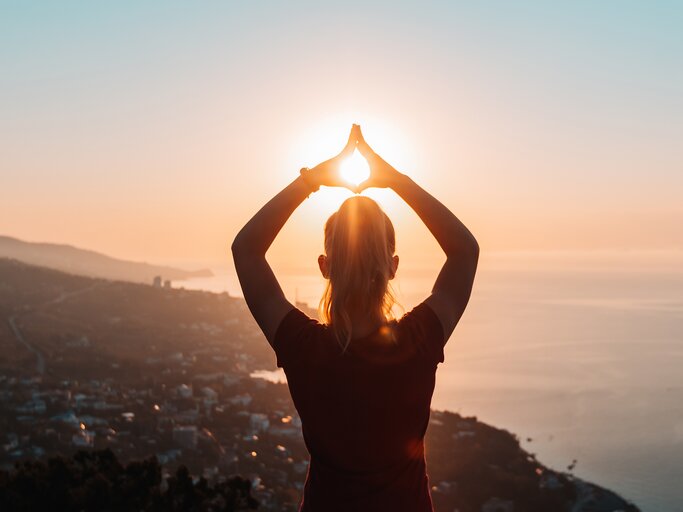 Frau macht Yoga beim Sonnenaufgang | © Getty Images/rbkomar