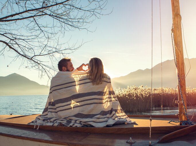 Paar sitzt romantisch am See | © Getty Images/swissmediavision