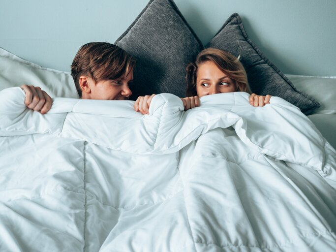 Mann und Frau liegen peinlich berührt im Bett | © Getty Images/	franckreporter