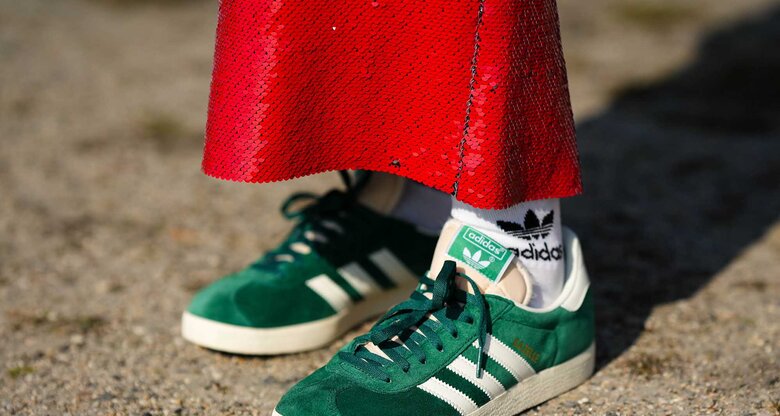 Eine Frau trägt grüne Adidas Gazelle mit einem roten Paillettenrock.  | © Getty Images/Edward Berthelot