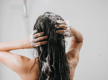Junge brünette Frau steht unter der Dusche und wäscht sich die Haare | © Adobe Stock/sarayutsridee