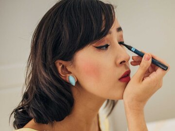 Junge Frau trägt Eyeliner vor dem Spiegel auf | © Getty Images/South_agency