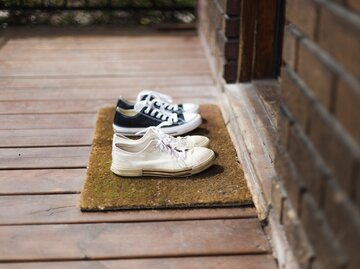 Schuhe stehen auf einem Fußabtreter vor der Haustür | © Getty Images/LindaRaymondPhotography