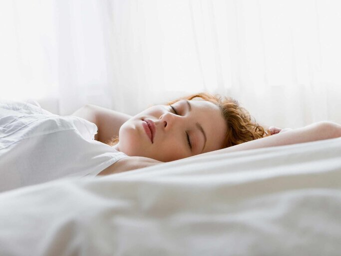Frau schläft im Bett | © Getty Images/Jose Luis Pelaez